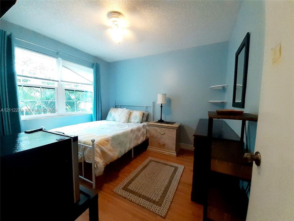 Bedroom featuring wood-finish flooring, dual-pane windows, and wall-mounted shelving