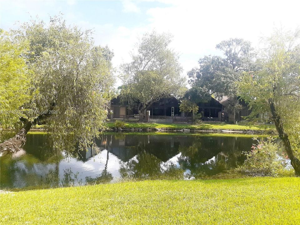 Waterfront property featuring a manicured lawn, mature trees, and a screened-in porch