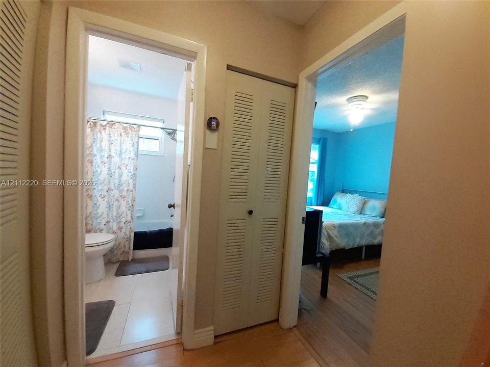 Neutral interior featuring wood-finish flooring, white louvered bi-fold doors, and a ceiling-mounted light fixture