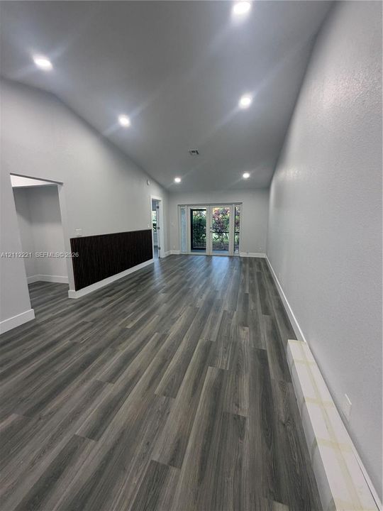 Interior space featuring a vaulted ceiling, wood-finish flooring, recessed lighting, and a dark-toned vertical slat accent wall