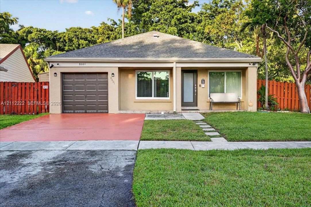 Single-story residence featuring a shingled roof, attached one-car garage, painted stucco exterior, glass-panel entry door, and perimeter privacy fencing