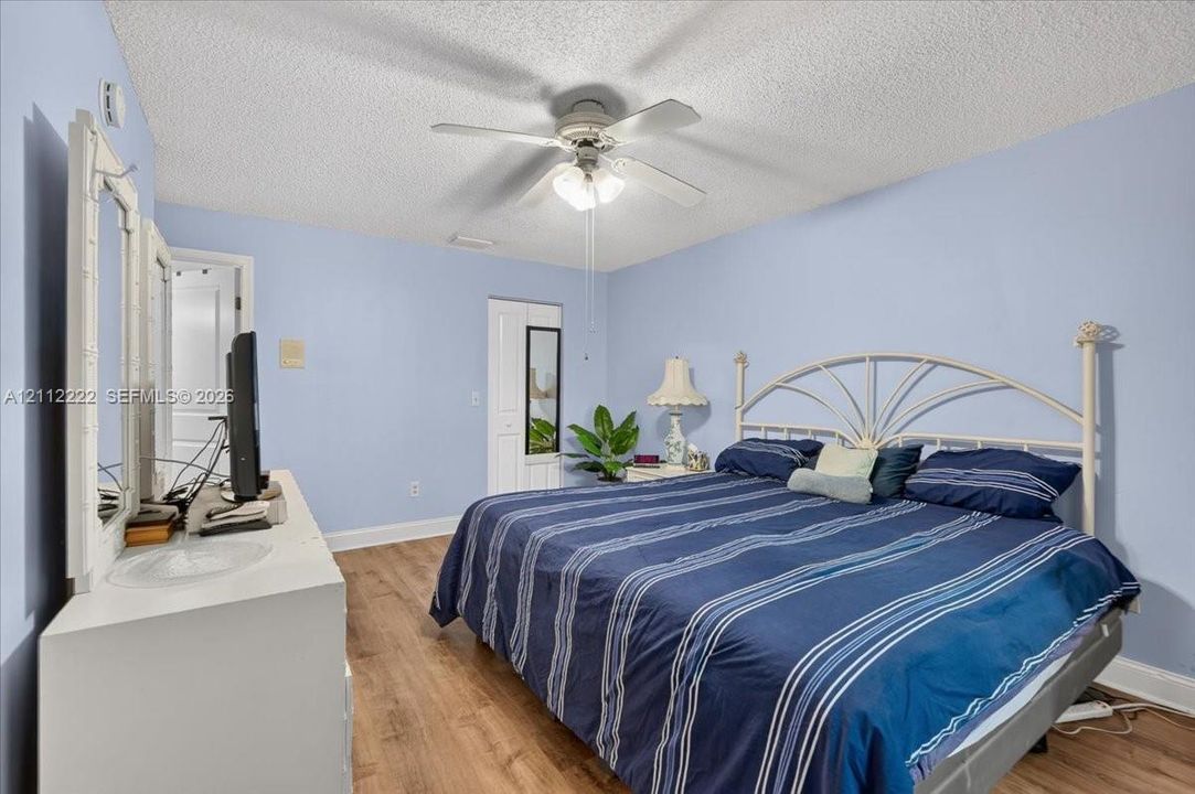 Wood-finish flooring, ceiling fan with integrated lighting, and white multi-panel closet door
