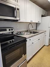 Kitchen featuring white shaker-style cabinetry, a stone-finish countertop, a stainless steel over-the-range microwave, a stainless steel range, and a gooseneck faucet