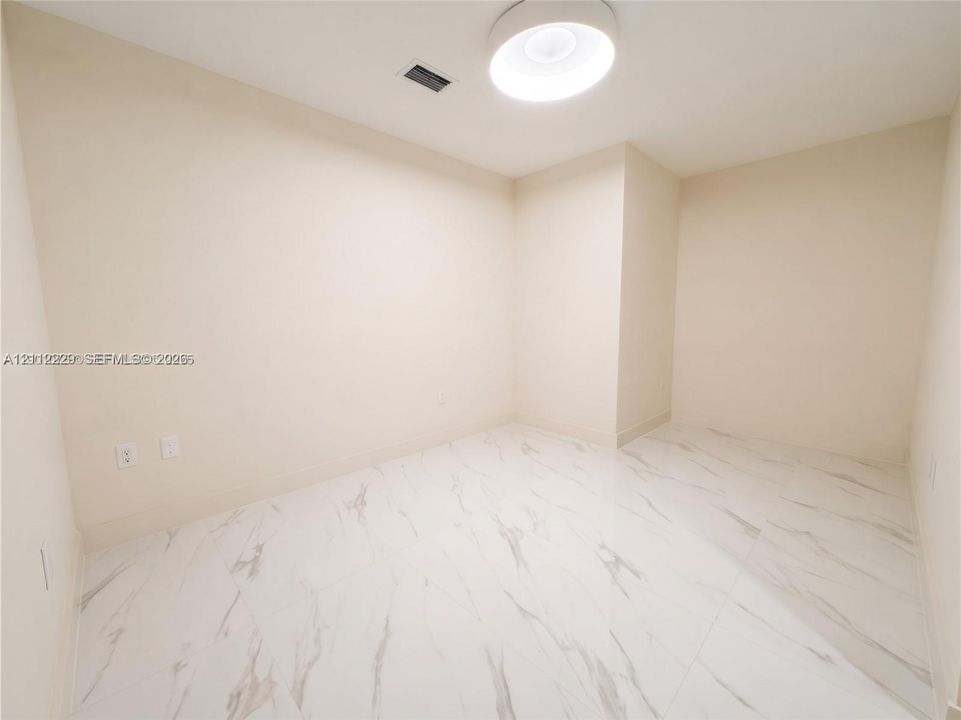Den featuring large-format white stone-finish tile flooring and a neutral color palette, illuminated by a contemporary circular flush-mount ceiling light
