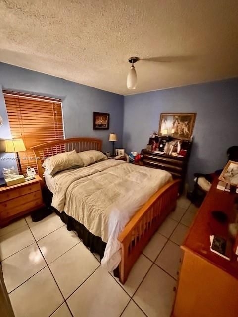 Room with light-colored tile flooring, neutral wall tones, window featuring horizontal blinds, and a centered pendant light fixture
