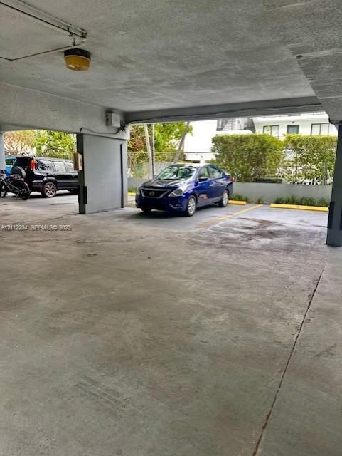 Covered parking area featuring concrete flooring, structural pillars, and designated parking stalls