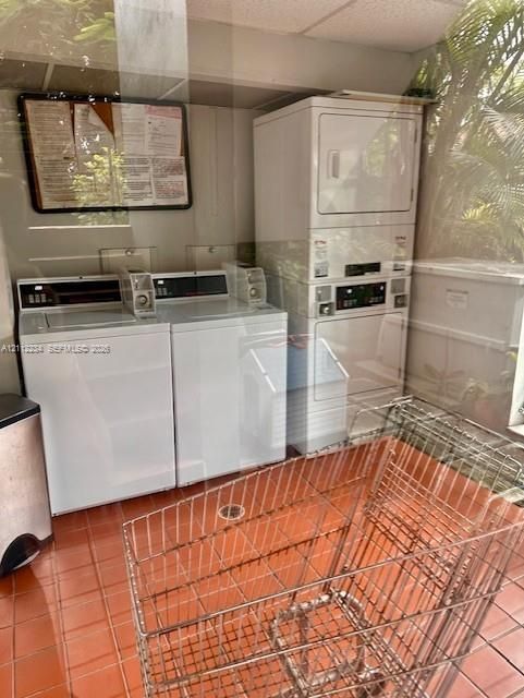 Laundry facility featuring two top-load washing machines and a stacked dryer unit, complemented by ceramic tile flooring