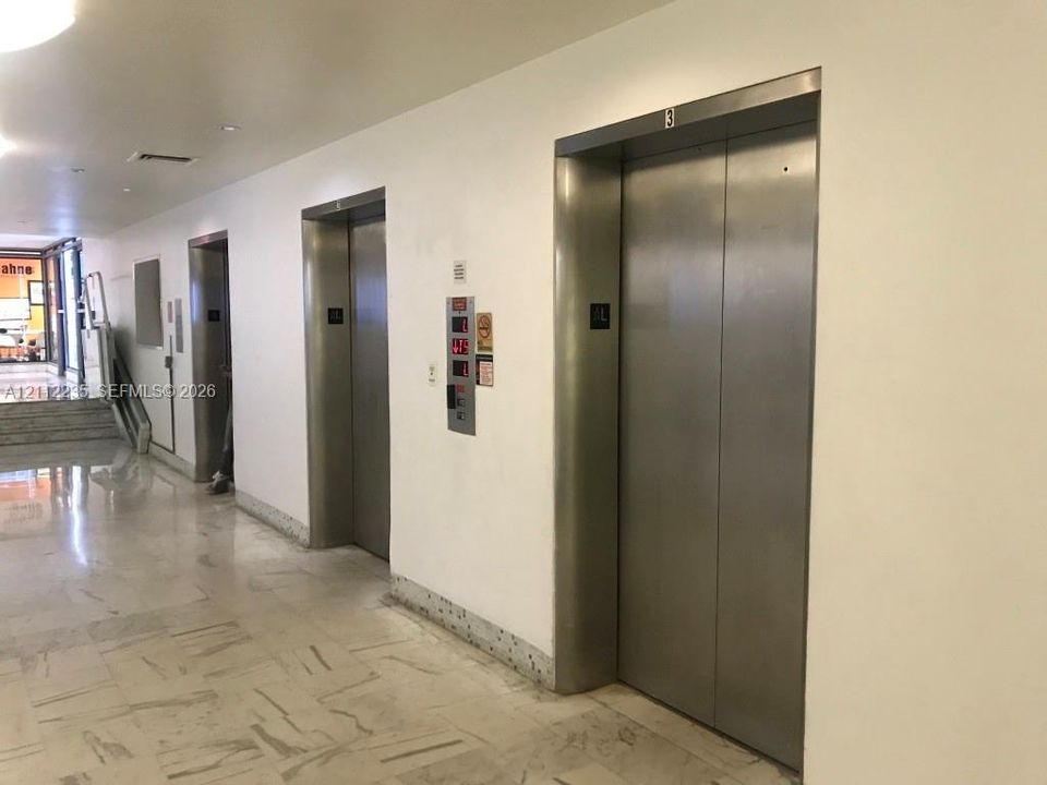 Elevator bank featuring brushed stainless steel doors and polished stone flooring