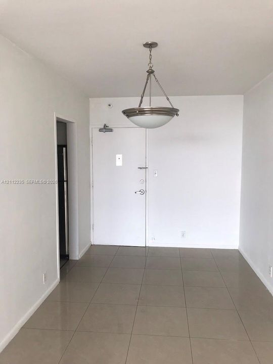 Large-format tile flooring, neutral walls, and a brushed-nickel semi-flush mount light fixture with a glass bowl shade