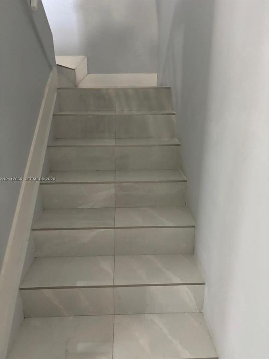 Staircase finished with large-format light-toned tile featuring subtle veining, complemented by smooth painted walls