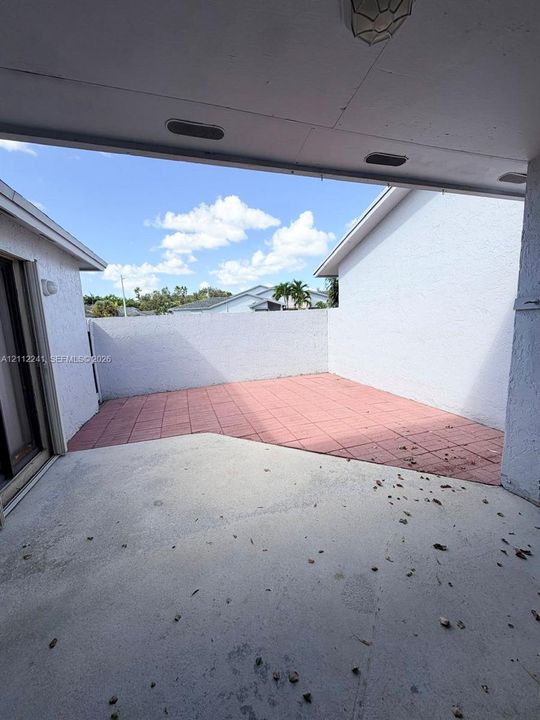 Covered patio featuring concrete flooring, a tiled floor section, and a stucco privacy wall