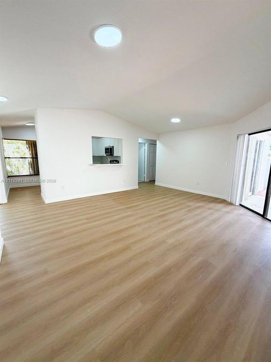 Vaulted ceilings, wood-finish flooring, recessed lighting, pass-through kitchen opening, and sliding glass door