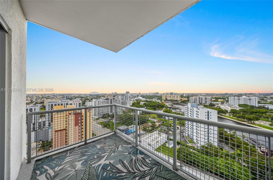 Private balcony with a metal railing and concrete flooring, featuring an expansive urban horizon backdrop