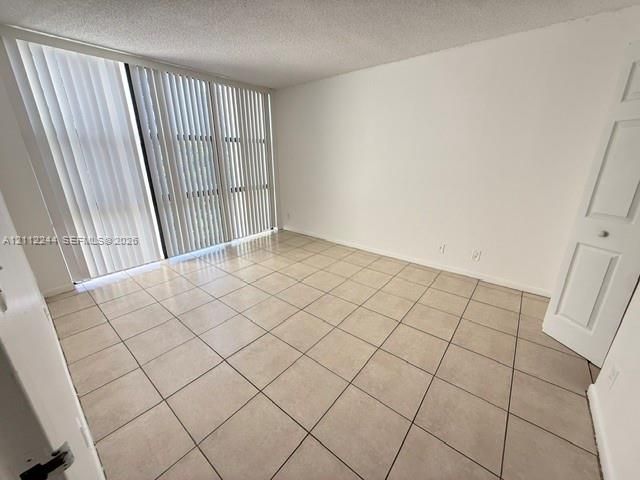 Floor-to-ceiling sliding glass doors, neutral tile flooring, and a multi-panel interior door