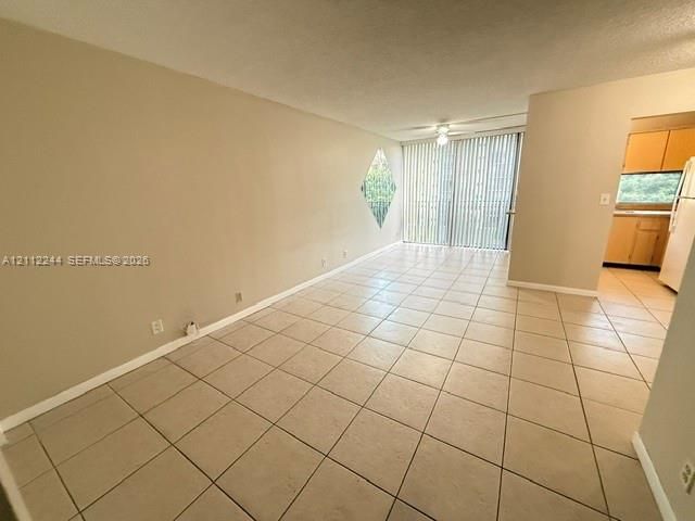 Neutral tile flooring, diamond-shaped accent window, and sliding glass door with vertical blinds