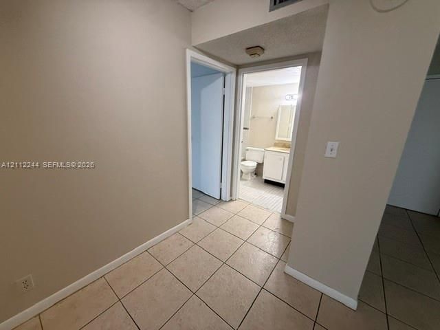 Neutral tile flooring, interior doors with white trim, and a built-in bathroom vanity with a basin sink