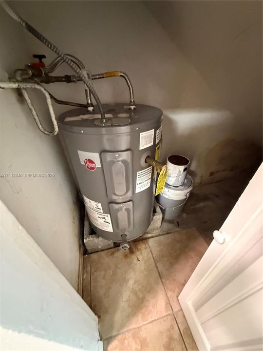Electric tank water heater situated on a raised masonry base with tiled flooring