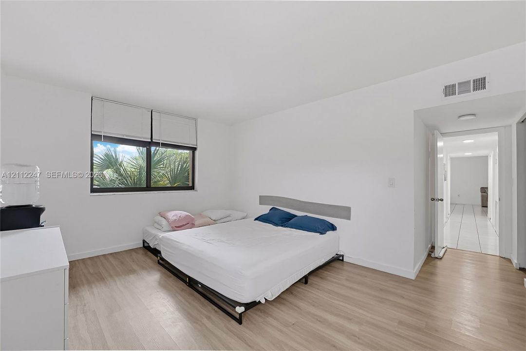 Room featuring wood-finish flooring, a neutral color palette, and a large window with blind treatments