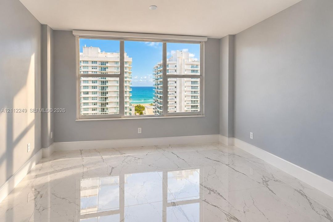 Large-format window featuring ocean and coastal scenery, finished with polished stone-look tile flooring and neutral wall paint