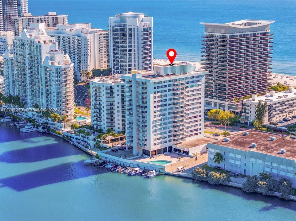 High-rise condominium featuring a waterfront location, private boat slips, an outdoor swimming pool, and coastal proximity