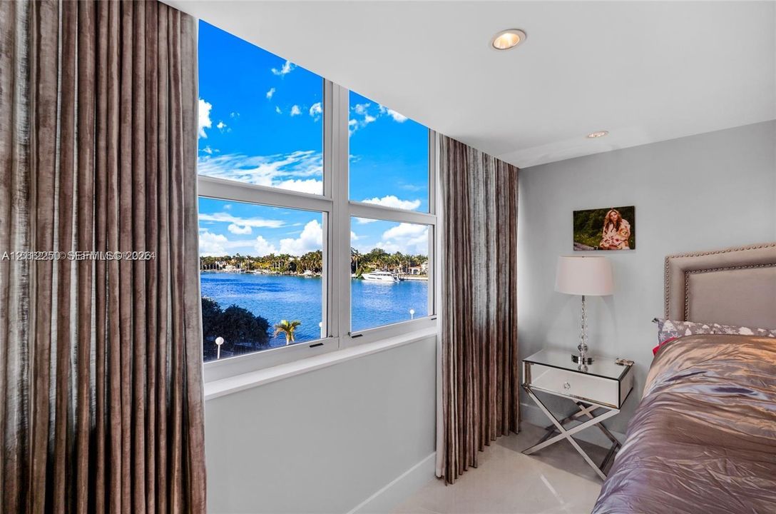 Large-format windows with multi-pane aluminum frames, recessed ceiling lighting, and expansive water exposure