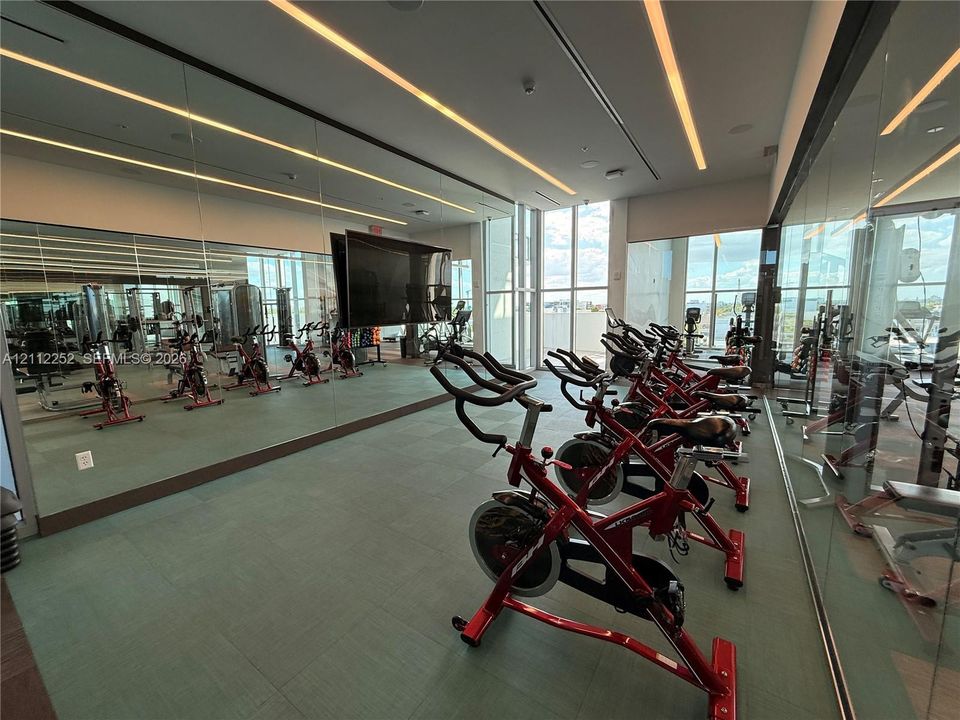 Fitness center featuring floor-to-ceiling mirrors, large-format tile flooring, linear recessed lighting, and extensive windows