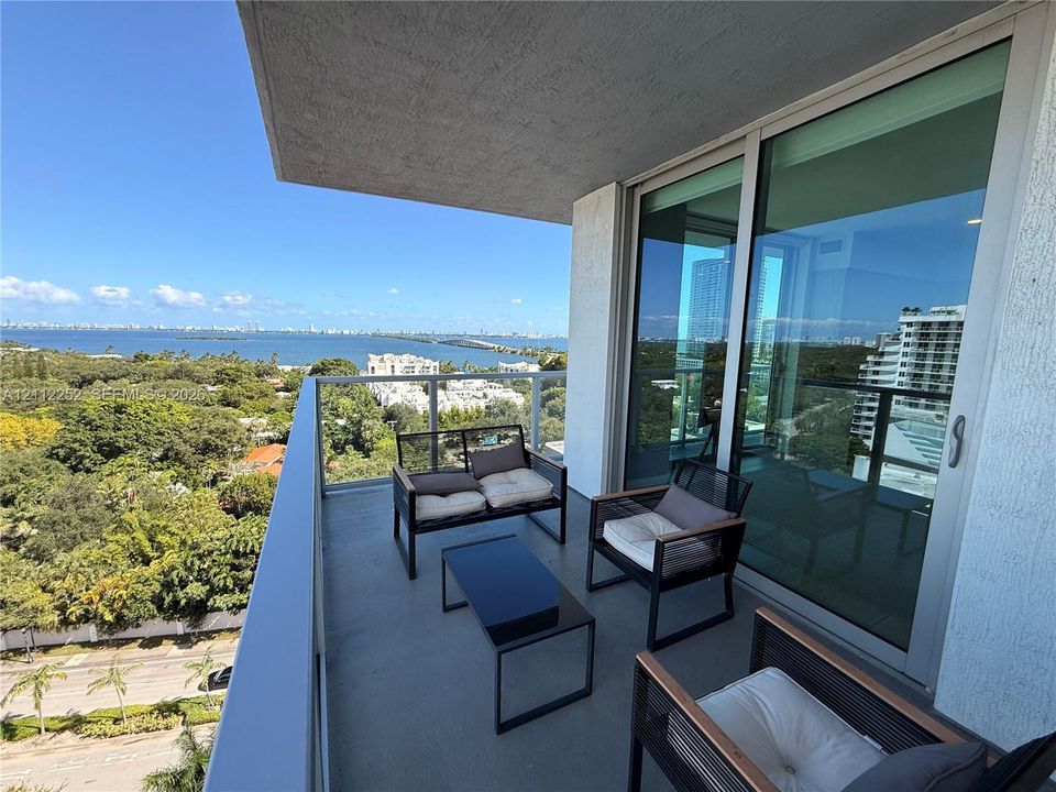 Private balcony featuring a glass-panel railing, concrete flooring, and full-height sliding glass doors