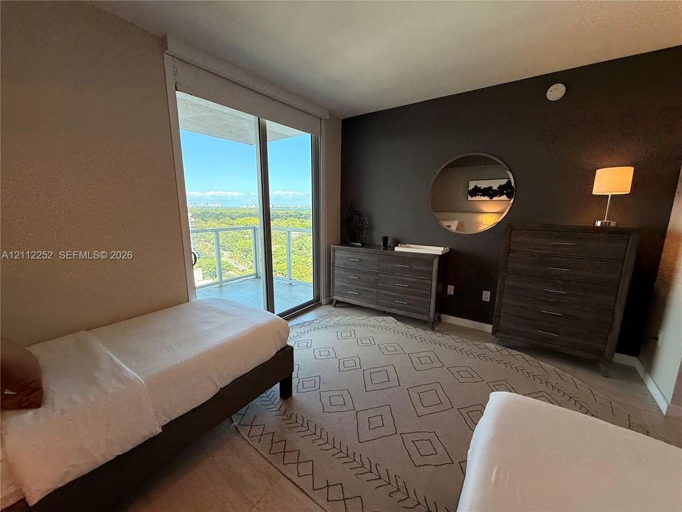Floor-to-ceiling glass sliding door, balcony with glass railing, wood-finish flooring, and accent wall