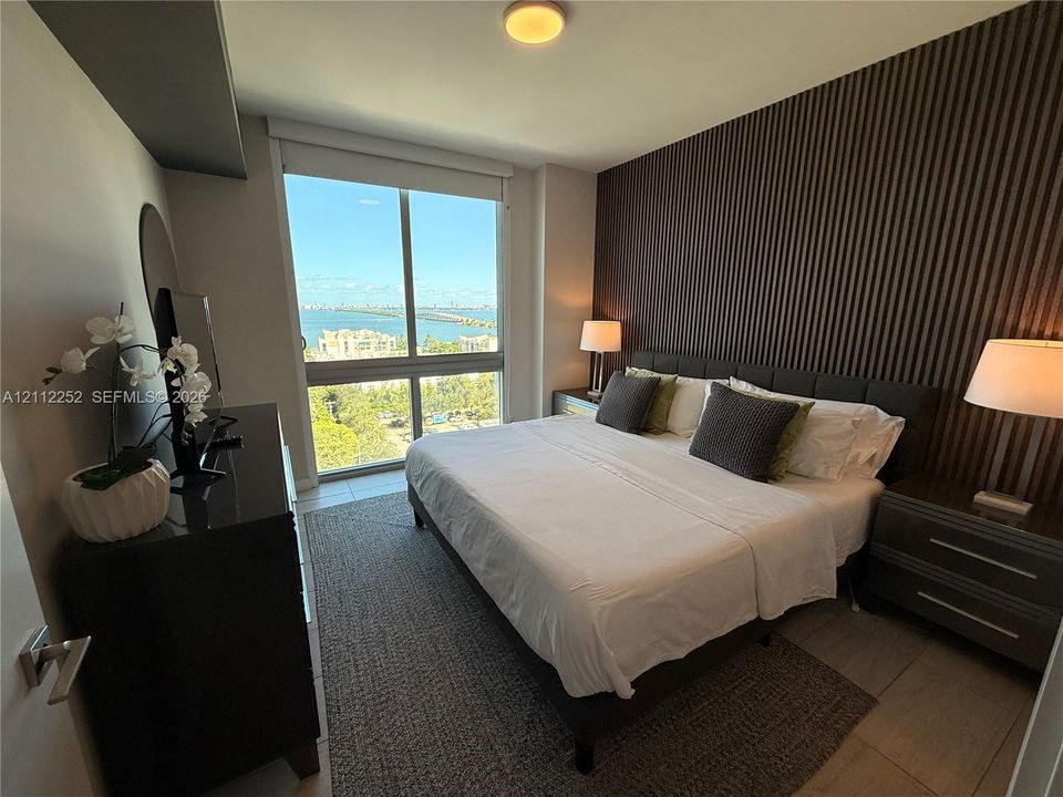 Floor-to-ceiling windows, dramatic vertical-slat accent wall, and ceramic tile flooring