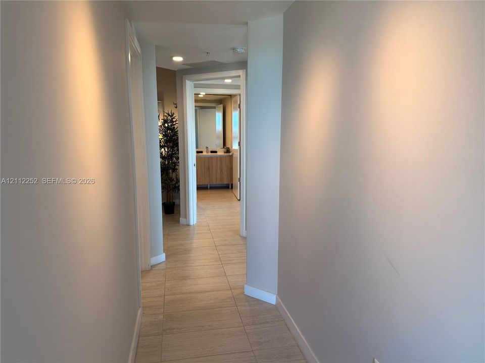 Hallway featuring neutral-toned wall paint, large-format tile flooring, and recessed ceiling lighting