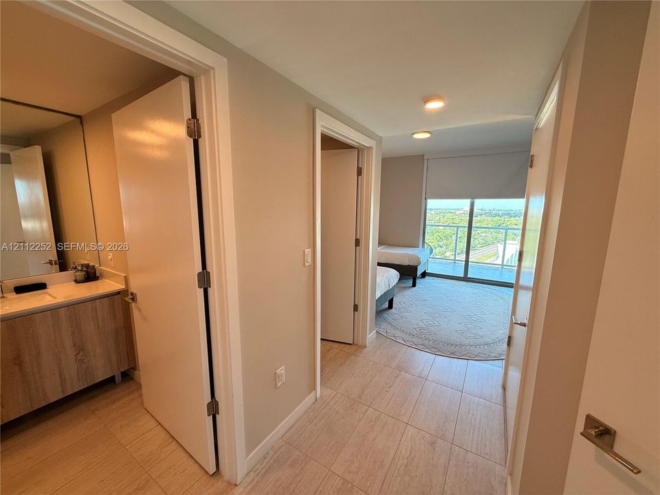 Hallway featuring tile flooring, light wood-finish vanity with countertop, and sliding glass door with balcony access