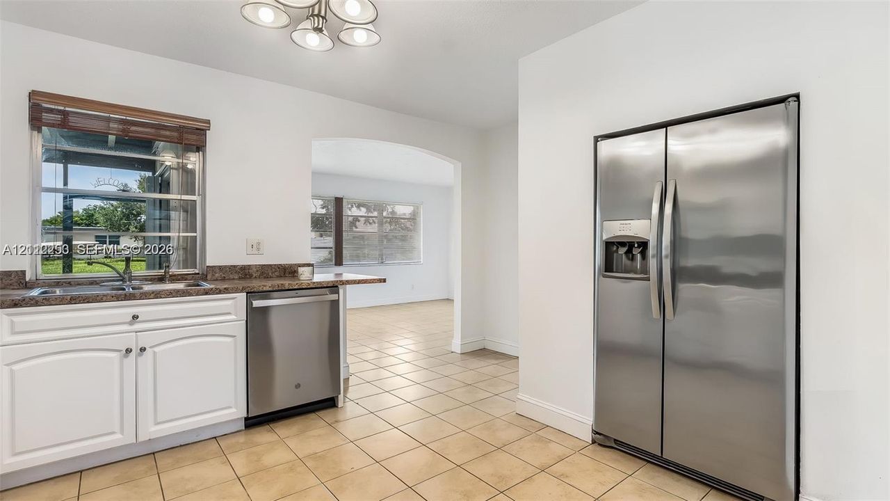 Kitchen featuring white cabinetry, stone-finish countertops, stainless steel appliances, ceramic tile flooring, and a multi-light fixture