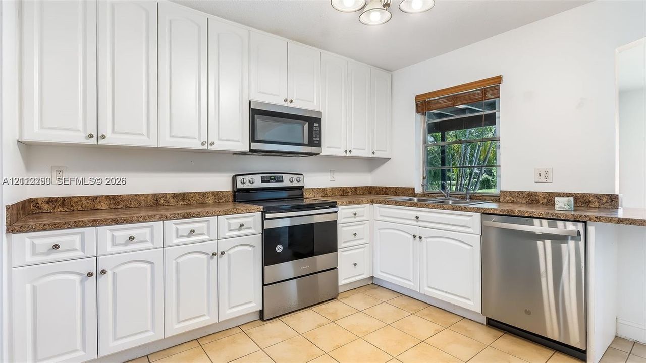 Kitchen featuring white cabinetry, stainless steel appliances, ceramic tile flooring, and a double-basin sink
