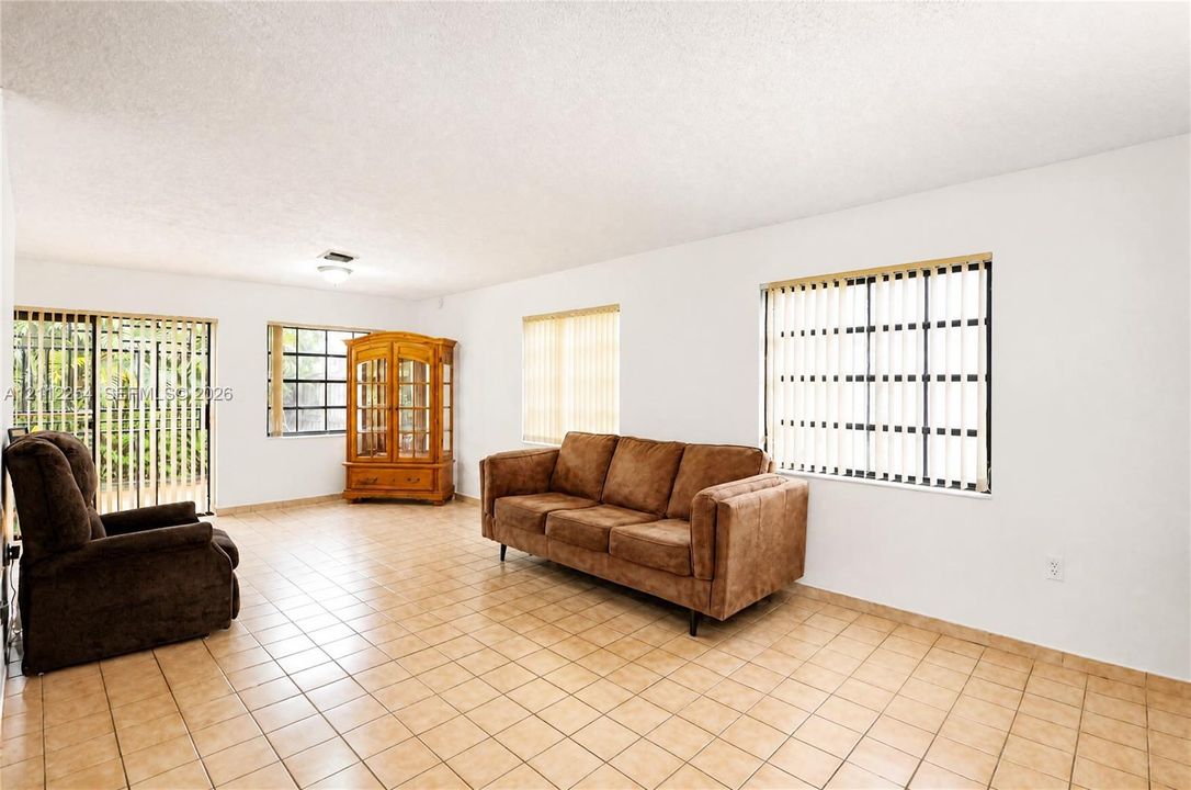 Ceramic tile flooring, multiple windows with vertical blinds, and sliding glass doors