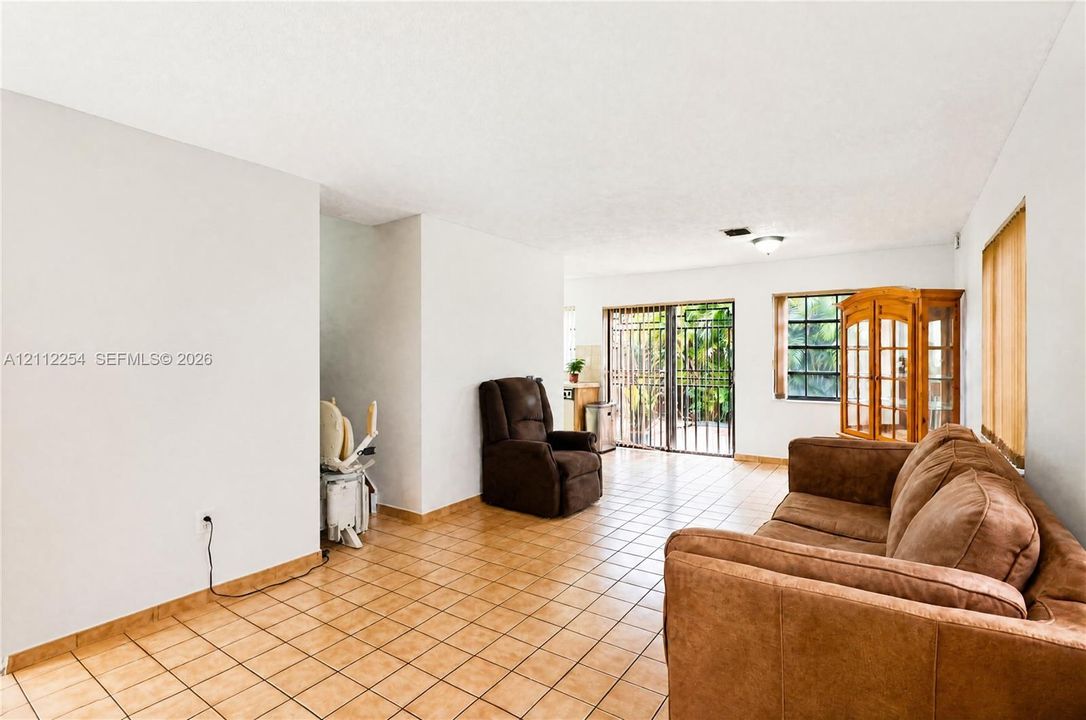 Ceramic tile flooring, sliding glass door with security bars, and windows with multi-pane grid detailing