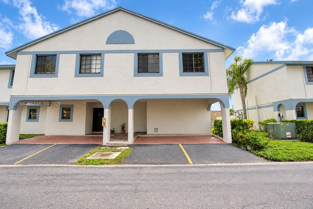 Two-story stucco exterior with arched portico, covered parking, and multi-pane windows