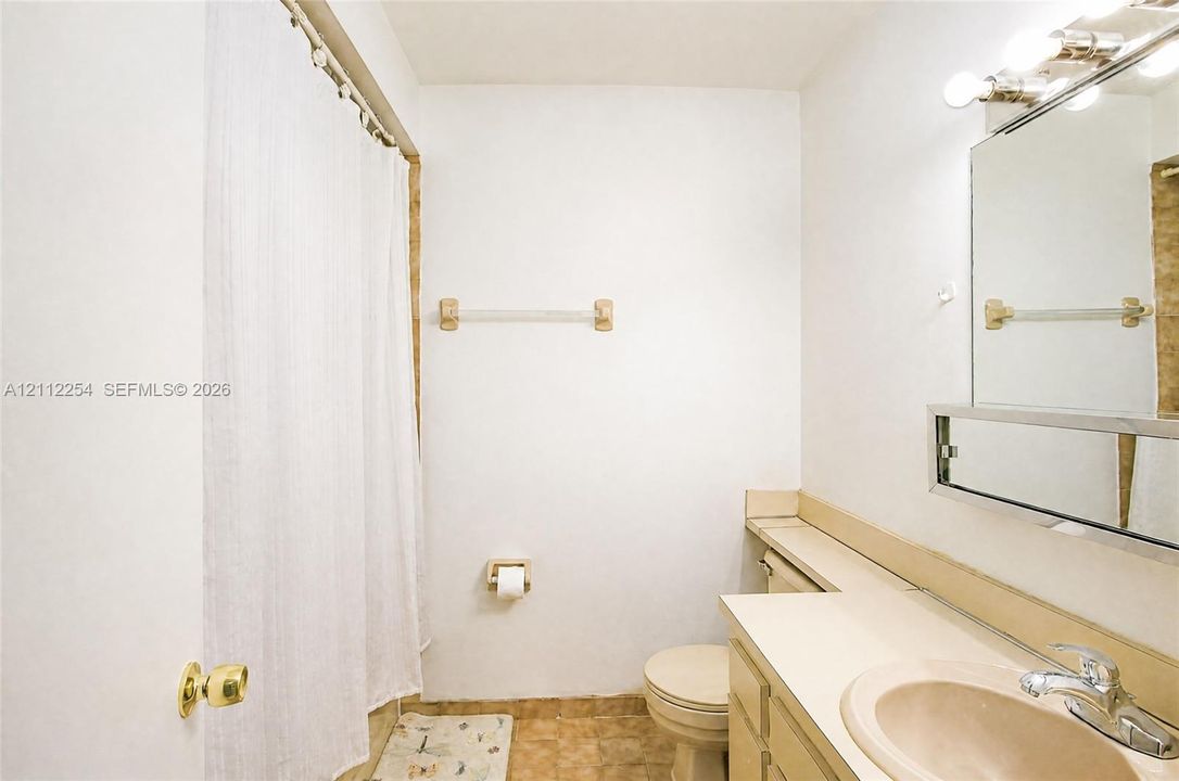 Bathroom featuring a vanity with an integrated basin, a wall-mounted mirror, a multi-bulb light fixture, a toilet, and a shower-tub combination