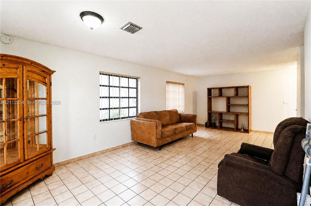 Interior space featuring neutral-toned tile flooring, recessed window grids, and built-in wooden shelving