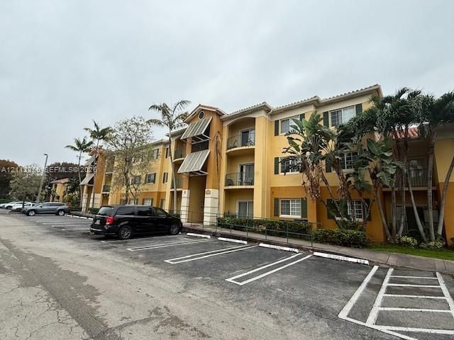Three-story exterior featuring a stucco facade, tile roofline, decorative window shutters, and arched balcony openings