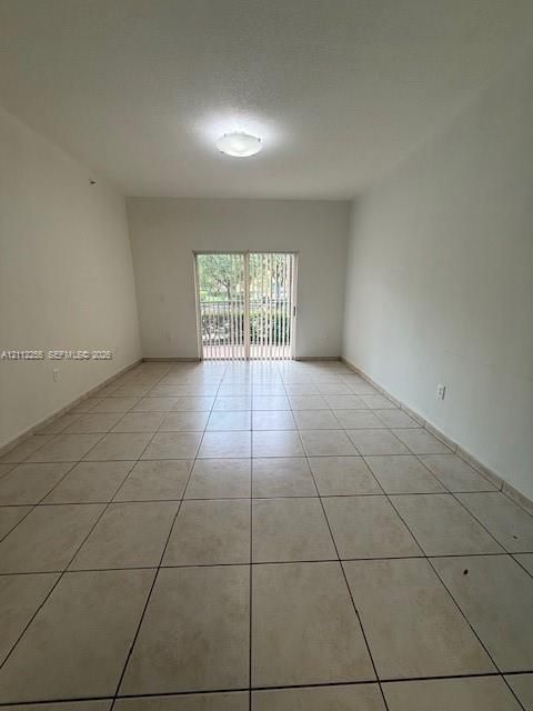 Neutral-toned ceramic tile flooring, flush-mount overhead lighting, and sliding glass doors featuring vertical blinds