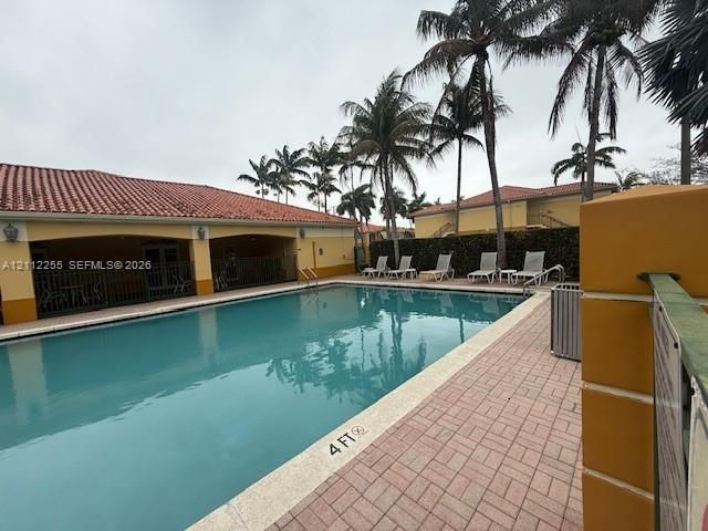 Swimming pool with masonry deck, terra cotta tile roof, and mature palm trees