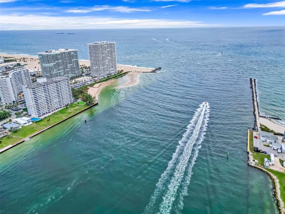 Aerial perspective of coastal inlet featuring direct ocean access, jetty, sandy shoreline, and expansive waterway