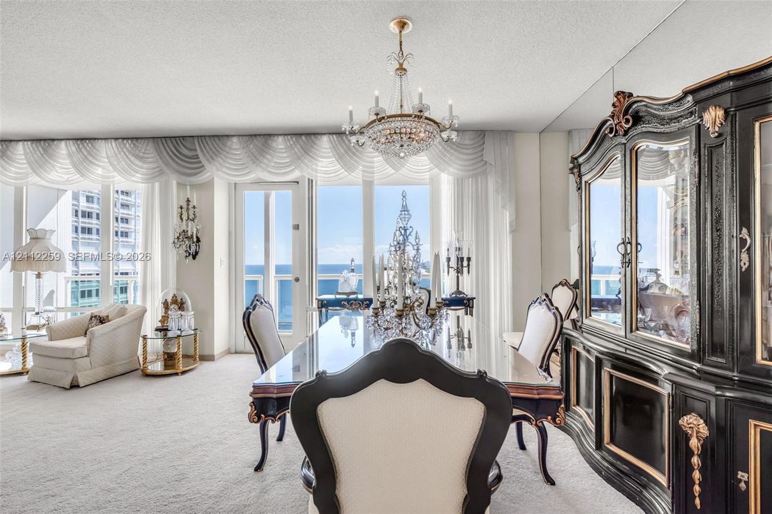 Floor-to-ceiling windows, crystal chandelier, mirrored wall paneling, and a glass-paneled door