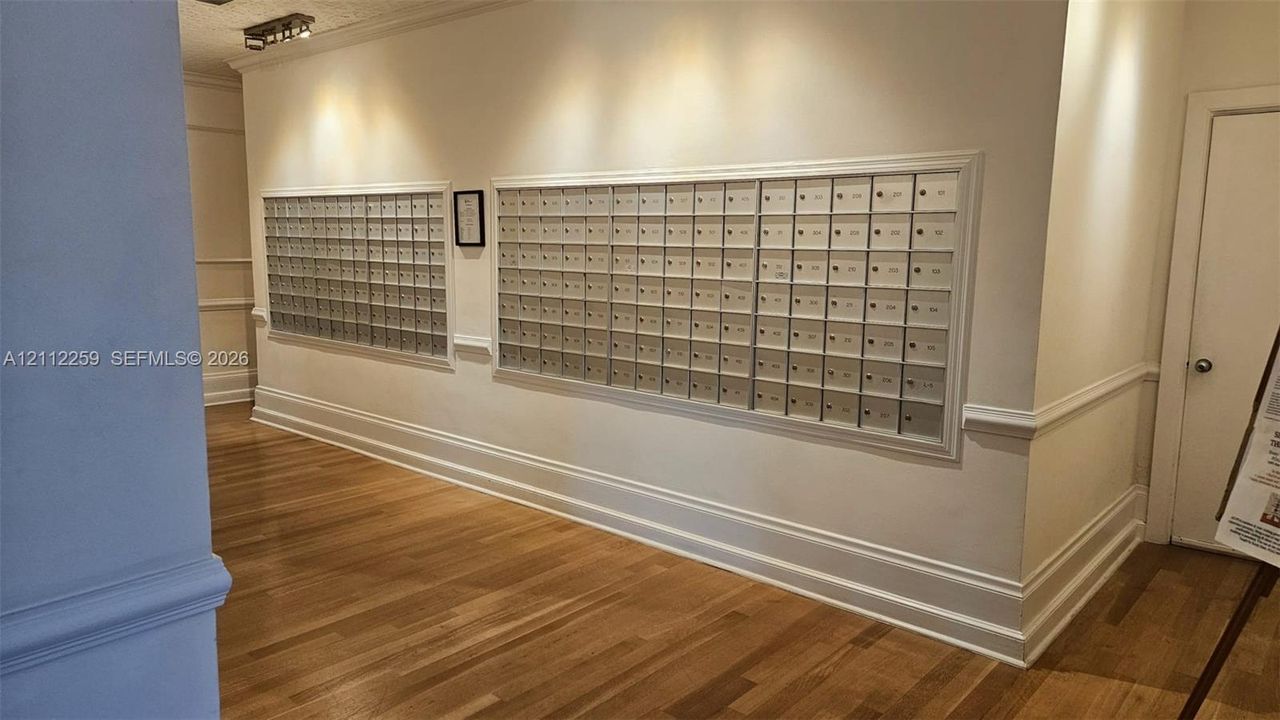 Common area featuring wall-mounted metal mailboxes, wood-finish flooring, crown molding, and chair rail detailing