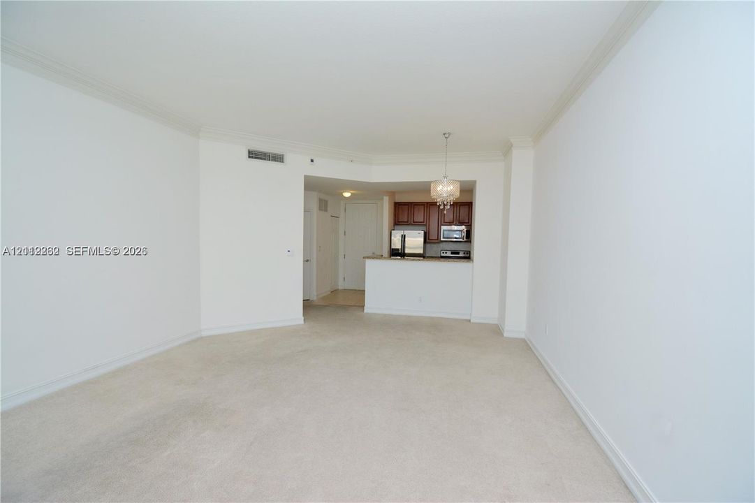 Open-concept area featuring crown molding, neutral carpeting, recessed ceiling lighting, and a kitchen with dark cabinetry and a breakfast bar