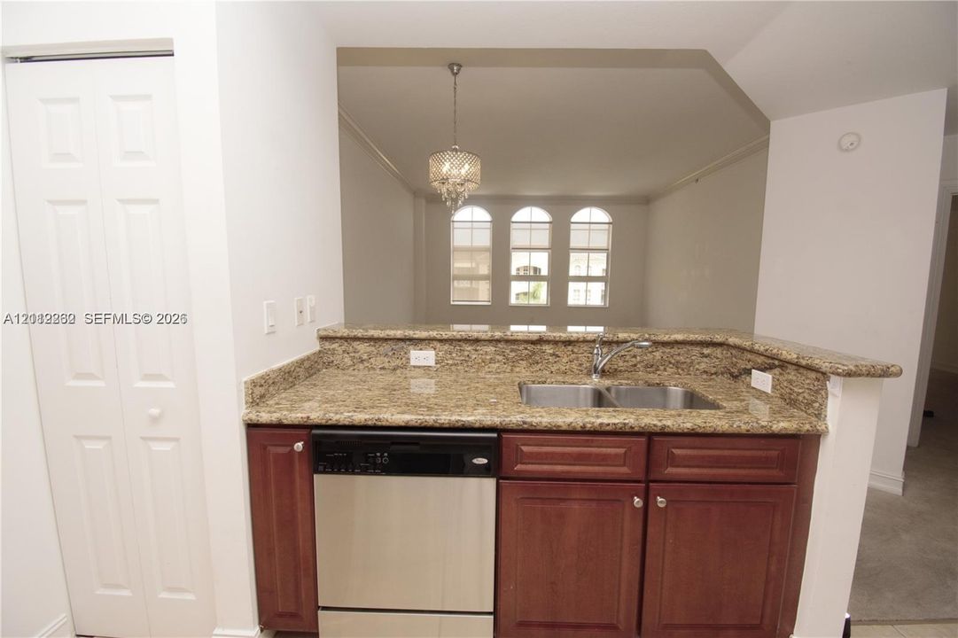 Kitchen featuring a stone-finish countertop, stainless steel dual-basin sink, built-in dishwasher, and wood-finish cabinetry