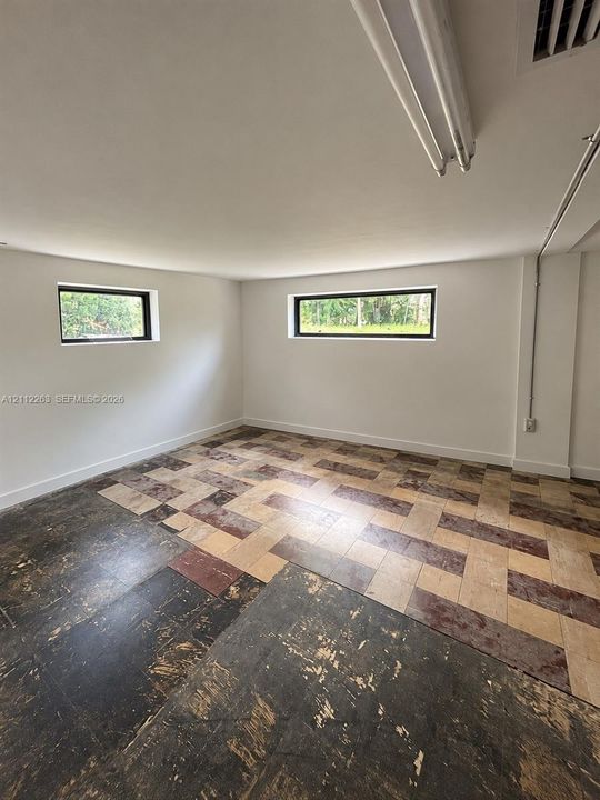 Interior space featuring horizontal awning windows, neutral wall finishes, and multi-tone tile flooring arranged in a basket-weave pattern