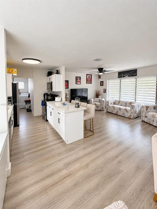 Kitchen featuring white cabinetry, a center island with light-toned countertops, and wood-finish flooring