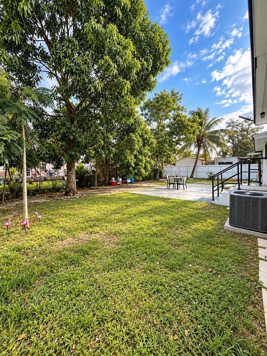Rear yard featuring a paved patio, perimeter fencing, mature trees, and ground-level landscaping