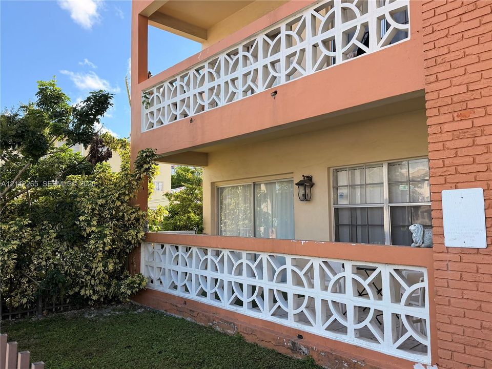 Two-story exterior featuring painted brick facade, decorative white geometric concrete screening, sliding glass doors, and attached wall-mounted lantern-style exterior lighting
